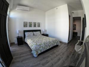 1 dormitorio con cama, suelo de madera y pared blanca en 310Guest-House La Vyda en San Juan