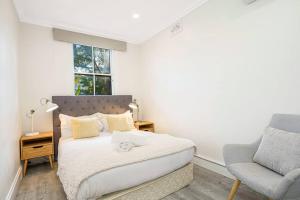 a bedroom with a bed and a chair and a window at Cozy 3 bedroom terrace in CBD in Sydney