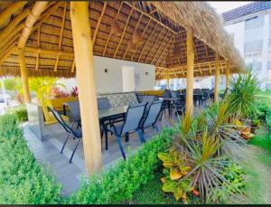 a patio with a table and chairs under a straw roof at Rincón del sol depa en Manzanillo colima in Manzanillo