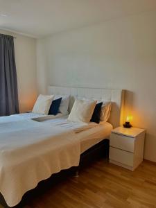 a bedroom with a large white bed with a night stand at Sunnuhlíð 19 in Akureyri