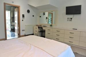 a bedroom with a bed and a desk and a television at Camden, London, Holloway Rooms in London