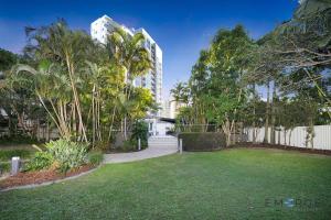 un patio con palmeras y una valla blanca en Ipanema Holiday Resort, en Gold Coast