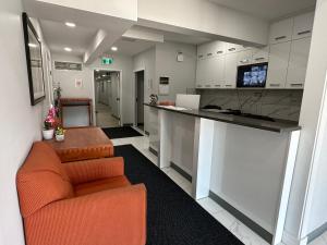 a living room with an orange couch and a kitchen at RAMSHORN MOTEL in Lumby