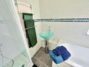 een badkamer met een wastafel en een bad met een blauwe handdoek bij New Brighton Beach in Wallasey
