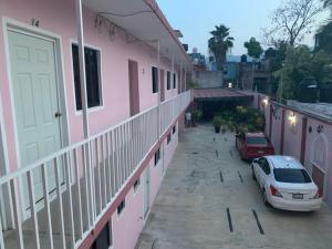 un'auto parcheggiata in un parcheggio accanto a un edificio rosa di Hotel Jacaranda a Tuxtla Gutiérrez