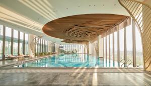 a large swimming pool in a building with windows at Aloft Yantai in Yantai