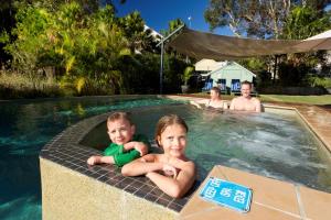 two children are sitting in a swimming pool at Blueys Retreat in Blueys Beach