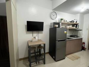 a kitchen with a refrigerator and a small table with stools at Stylish 1BR Condo @ SM Southmall in Manila