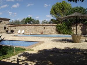 una piscina frente a un edificio con sombrilla en Set of rural houses in the center of Andalucia, en Humilladero