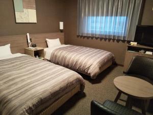 Pokój hotelowy z 2 łóżkami i krzesłem w obiekcie Hotel Route-Inn Nishinasuno-2 w mieście Nasushiobara