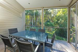 a dining room with a glass table and chairs at Blueys Retreat in Blueys Beach
