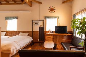 a bedroom with a bed and a couch and a tv at Nakijin Lodge ぺんさじょうやー in Nakijin