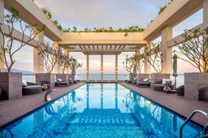 einen Pool in einem Hotel mit Stühlen und Aussicht in der Unterkunft Paris Deli Danang Beach Hotel in Đà Nẵng