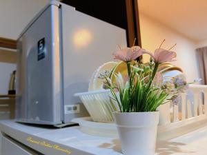 a vase with flowers on a counter next to a microwave at Peanut Butter Homestay #Trefoil Setia City in Setia Alam