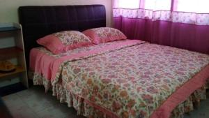 uma cama cor-de-rosa com lençóis cor-de-rosa e almofadas cor-de-rosa em Homestay Tambun Ipoh em Tambun