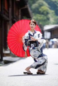 un joven en un kimono sosteniendo un paraguas rojo en 日本文化を体験できるゲストハウス繭子の宿, en Hachinohe