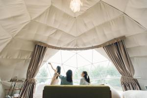 three women in a room with a large window at LUONTE 霧の高原 Glamping 