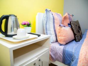 a bed with a table with a coffee maker and pillows at Annex Lodge @ Ndabeni in Cape Town