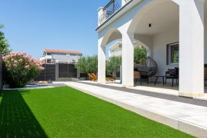 a yard with green grass and a white house at Villa Kalani in Kaštela