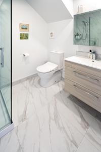 La salle de bains blanche est pourvue de toilettes et d'un lavabo. dans l'établissement Harmony Hideout 2 bed 2 bath, à Christchurch
