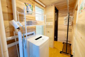 uma casa de banho com máquina de lavar e secar roupa num quarto em Furano Log House Farm Resort em Furano