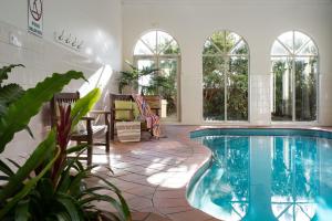 a large swimming pool in a room with windows at Courthouse Orchid Villa 6 in Daylesford