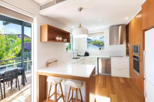 a kitchen with a island with stools and a balcony at Emerald Noosa in Noosa Heads