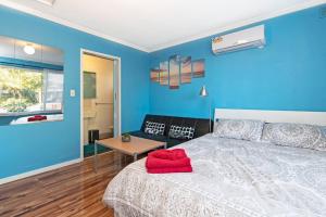 Dormitorio azul con cama y mesa en Ocean Views Apartment 2 min walk to train & ocean, en Halletts Cove