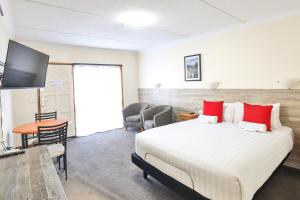 a bedroom with a large bed with red pillows at Boulevard Motor Inn in Mildura