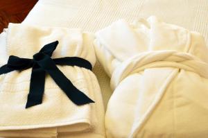 トリノにあるFeria D'Agostoのベッドの上に黒弓と白いタオル2枚
