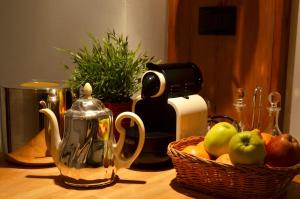 トリノにあるFeria D'Agostoのコーヒーメーカー付きのテーブルにフルーツバスケットを用意しています。