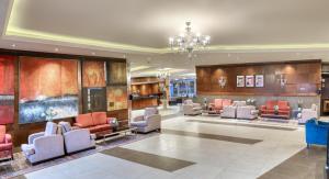 a lobby with couches and chairs and a chandelier at Geneva Hotel in Amman