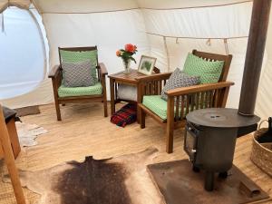 a living room with two chairs and a wood stove at Golden Bay Glamping in Takaka
