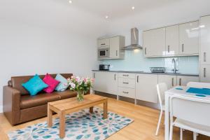 ein Wohnzimmer mit einem Sofa und einem Tisch sowie eine Küche in der Unterkunft The Lion Gate Mews in Kingston upon Thames