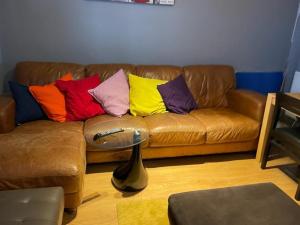 - un canapé en cuir brun avec des oreillers colorés dans l'établissement New Cross Hospital - 4 Bedrooms, 2 Bathrooms, Free Parking, à Wolverhampton