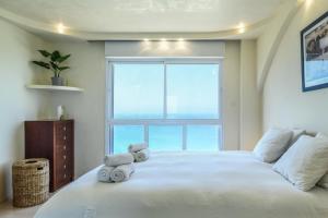 a bedroom with a white bed with two stuffed animals on it at Netanya Panoramic Sea-View Apt by Sea N' Rent in Netanya