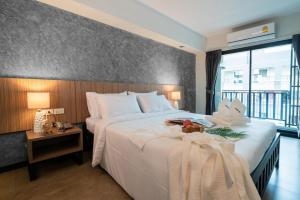 a bedroom with a large white bed and a large window at The Home Hotel SHA in Bangkok
