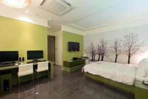 1 dormitorio con 1 cama y escritorio con 2 monitores en Ambassador Hotel, en Suncheon