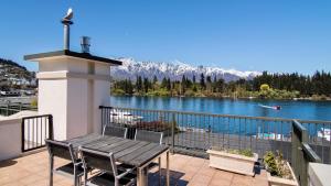 a table and chairs on a balcony with a view of a lake at The Waterfront in Queenstown