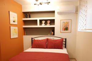 Schlafzimmer mit orangefarbenen Wänden und einem Bett mit roten Kissen in der Unterkunft Venizelou Comfort & Living I in Kavala