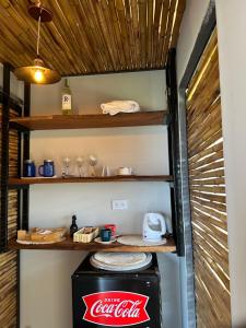 a coca cola refrigerator in a kitchen with wooden shelves at Glamping Las Rocas in Calima
