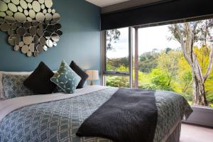 a bedroom with a bed and a large window at Daylesford Spa Villa 6 in Daylesford