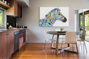 a kitchen with a table and a painting of a zebra at Daylesford Spa Villa 6 in Daylesford
