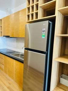 a stainless steel refrigerator in a kitchen with wooden cabinets at TMS Luxury Hotel in Quy Nhon