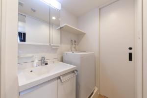 een witte badkamer met een wastafel en een koelkast bij LEGALAND Gakushuin Shita in Tokyo