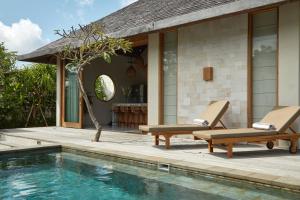 a swimming pool with two lounge chairs next to a house at Villa Cerah in Uluwatu