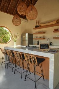 a kitchen with a large counter with chairs around it at Villa Cerah in Uluwatu