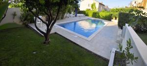 una piscina con un árbol en un patio en Villa Bakica, en Trogir