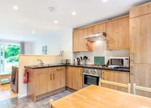 uma cozinha com armários de madeira, uma mesa e um micro-ondas em Amazing Home In Newquay With Indoor Swimming Pool, Wifi And Heated Swimming Pool em Newquay