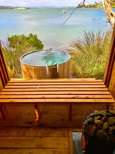 a hot tub sitting on a deck next to the ocean at Wingtons Glamping in Clarence Point